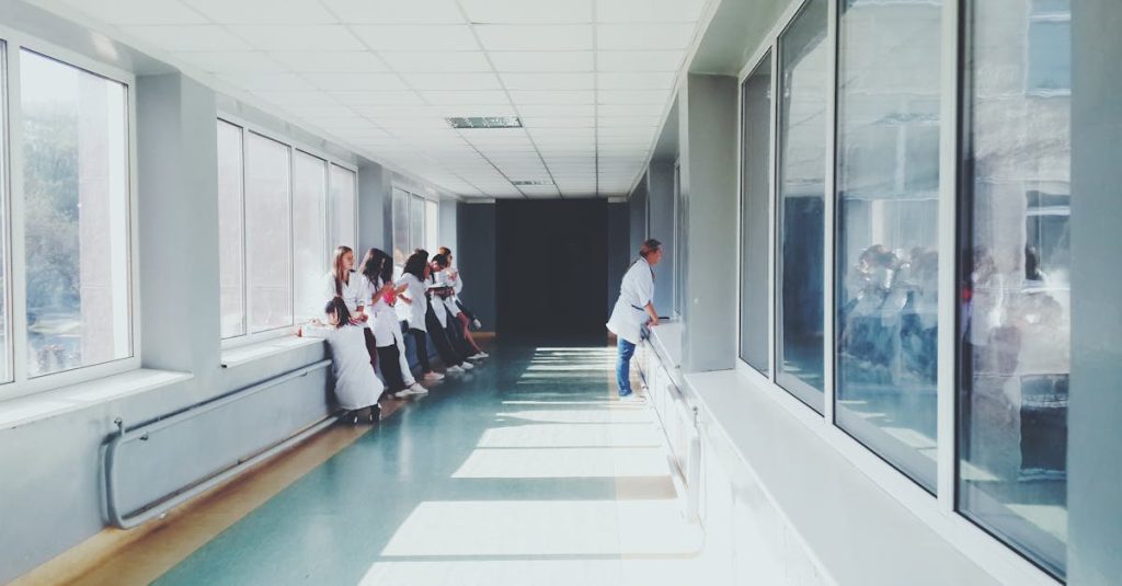A brightly lit hospital hallway with medical staff in white coats, conveying a professional healthcare environment.