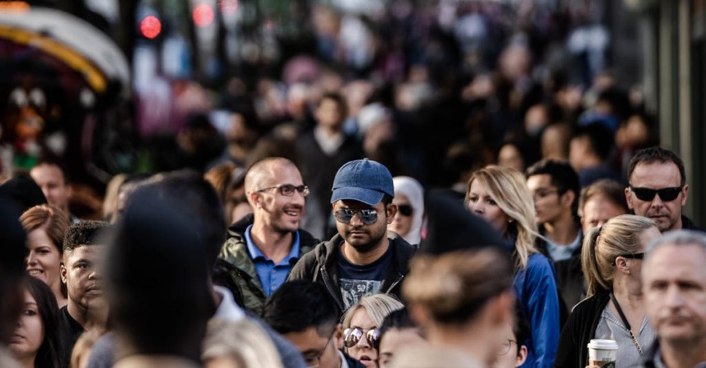 A bustling urban scene with diverse people walking on a tree-lined city street.